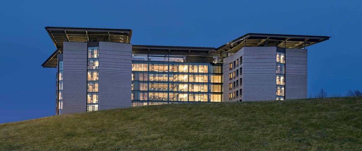 Exterior evening photo of building appearing over a grassy hill