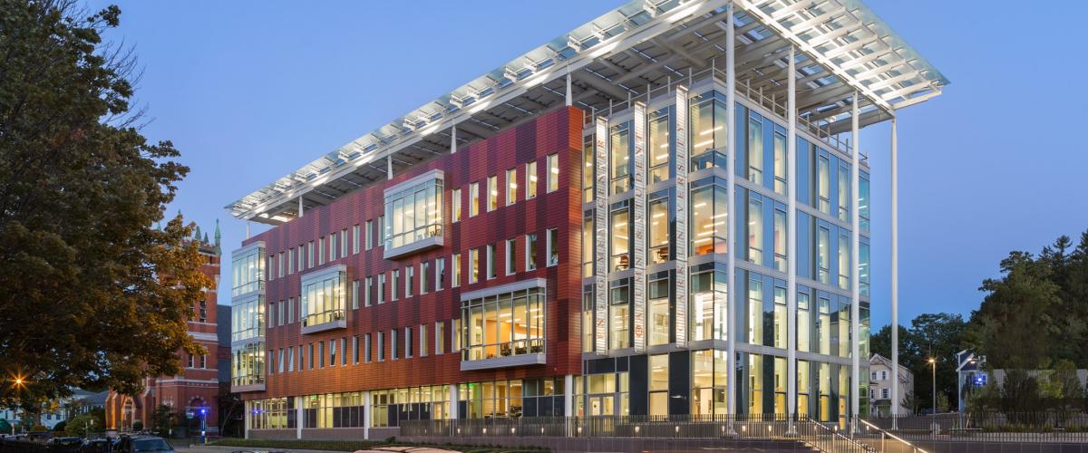 A 4 story academic building with a large white solar canopy structure above