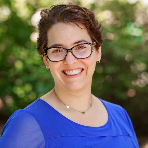 Woman with glasses, short brown hair, and a blue blouse